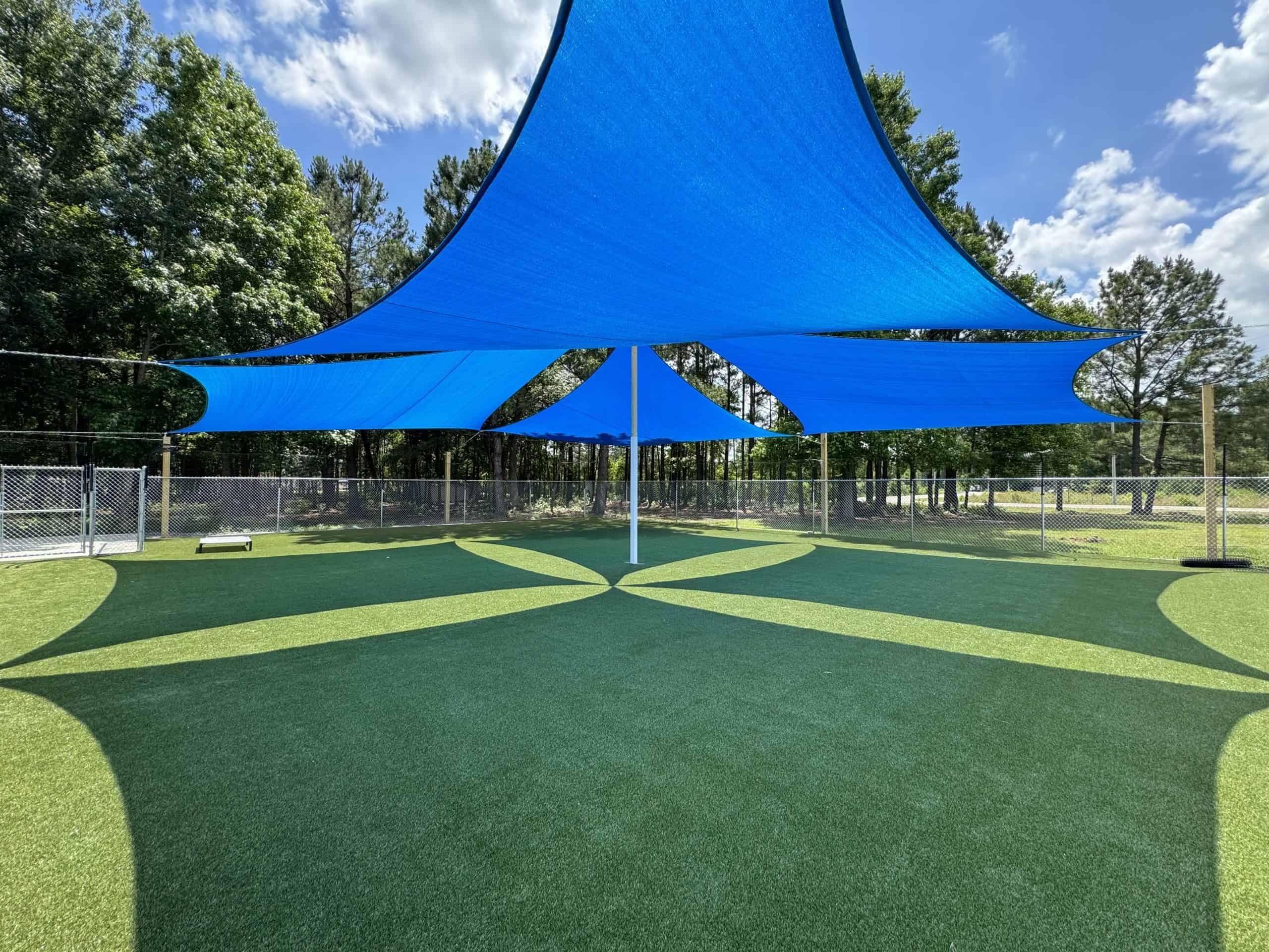 Large shaded outdoor play areas surfaced with industry-leading and patented K9 Grass by Foreverlawn.
